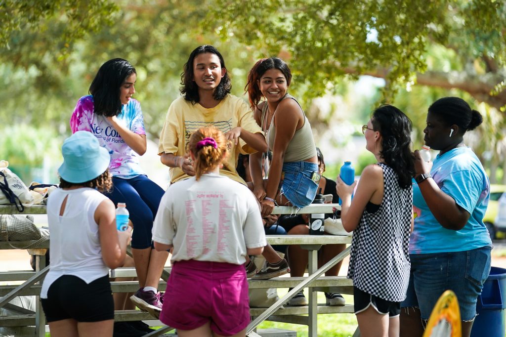 7 students sitting together actively talking to each other on Campus