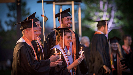Graduates hold candles during torch night